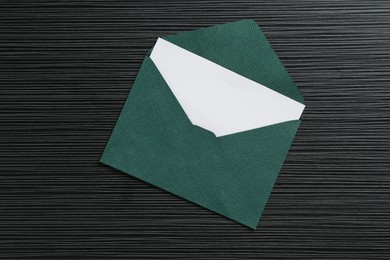 Photo of Blank invitation card and envelope on black textured table, top view