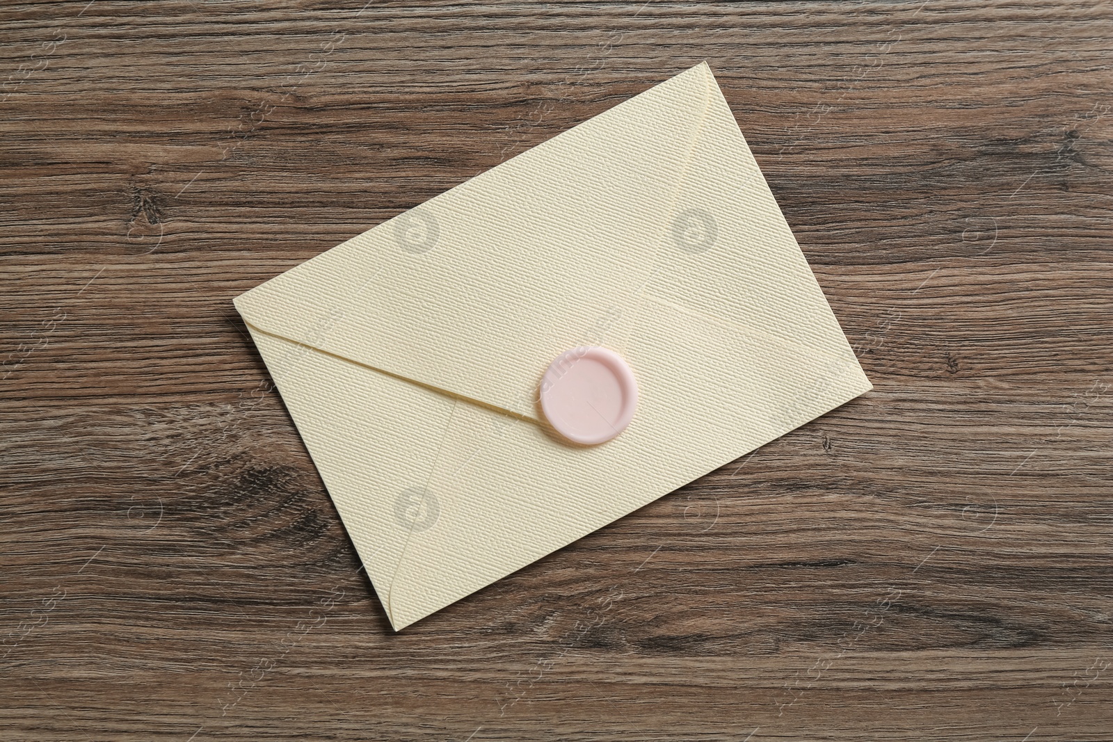 Beautiful invitation envelope with wax seal on wooden table, top view Photo of Beautiful invitation envelope with wax seal on wooden table, top view
