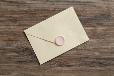 Photo of Beautiful invitation envelope with wax seal on wooden table, top view