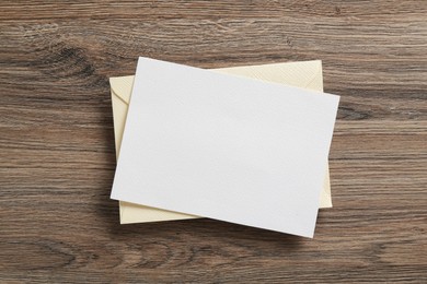 Photo of Blank invitation card and envelope on wooden table, top view. Space for design