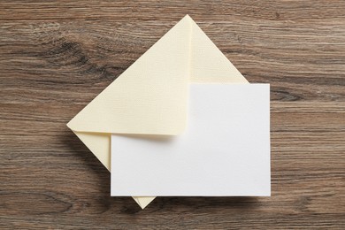 Photo of Blank invitation card and envelope on wooden table, top view. Space for design