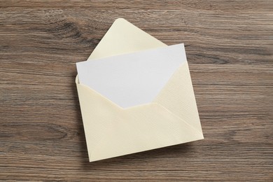 Photo of Blank invitation card and envelope on wooden table, top view