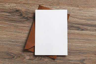 Photo of Blank invitation card and envelope on wooden table, top view. Space for design