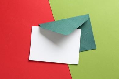 Photo of Blank invitation card and envelope on color background, top view. Space for design