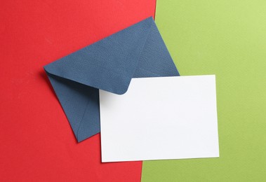 Photo of Blank invitation card and envelope on color background, top view. Space for design