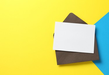 Photo of Blank invitation card and envelope on color background, top view. Space for design