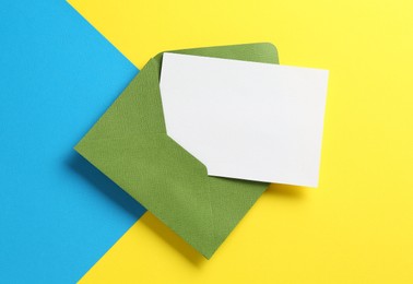 Photo of Blank invitation card and envelope on color background, top view. Space for design