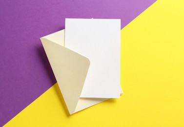 Photo of Blank invitation card and envelope on color background, top view. Space for design