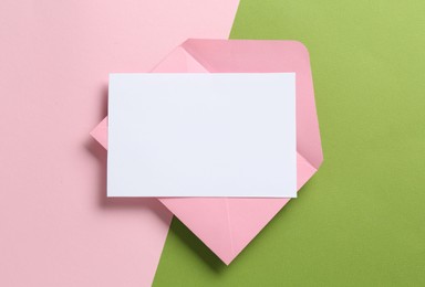 Photo of Blank invitation card and envelope on color background, top view. Space for design