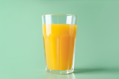 Photo of Tasty mango juice in glass on green background