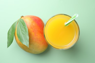 Photo of Tasty mango juice in glass and fresh fruit on green background, flat lay