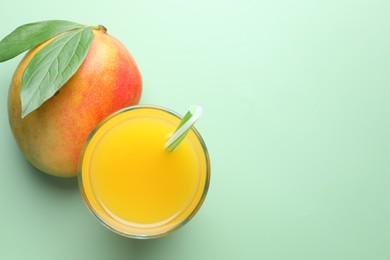 Photo of Tasty mango juice in glass and fresh fruit on green background, flat lay. Space for text