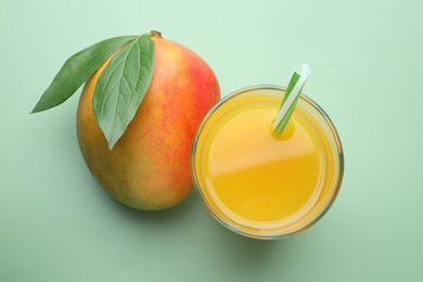 Photo of Tasty mango juice in glass and fresh fruit on green background, flat lay