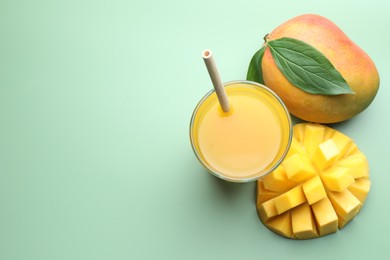 Photo of Tasty mango juice in glass and fresh fruits on green background, flat lay. Space for text