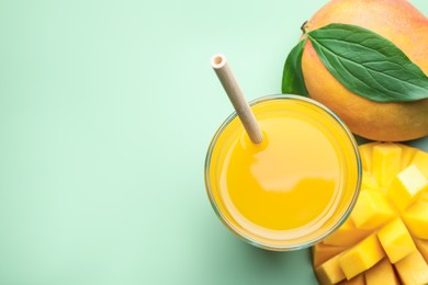 Photo of Tasty mango juice in glass and fresh fruits on green background, flat lay. Space for text
