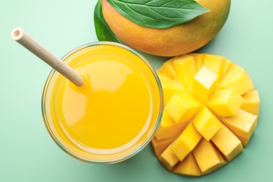 Photo of Tasty mango juice in glass and fresh fruits on green background, flat lay