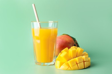 Photo of Tasty mango juice in glass and fresh fruits on green background