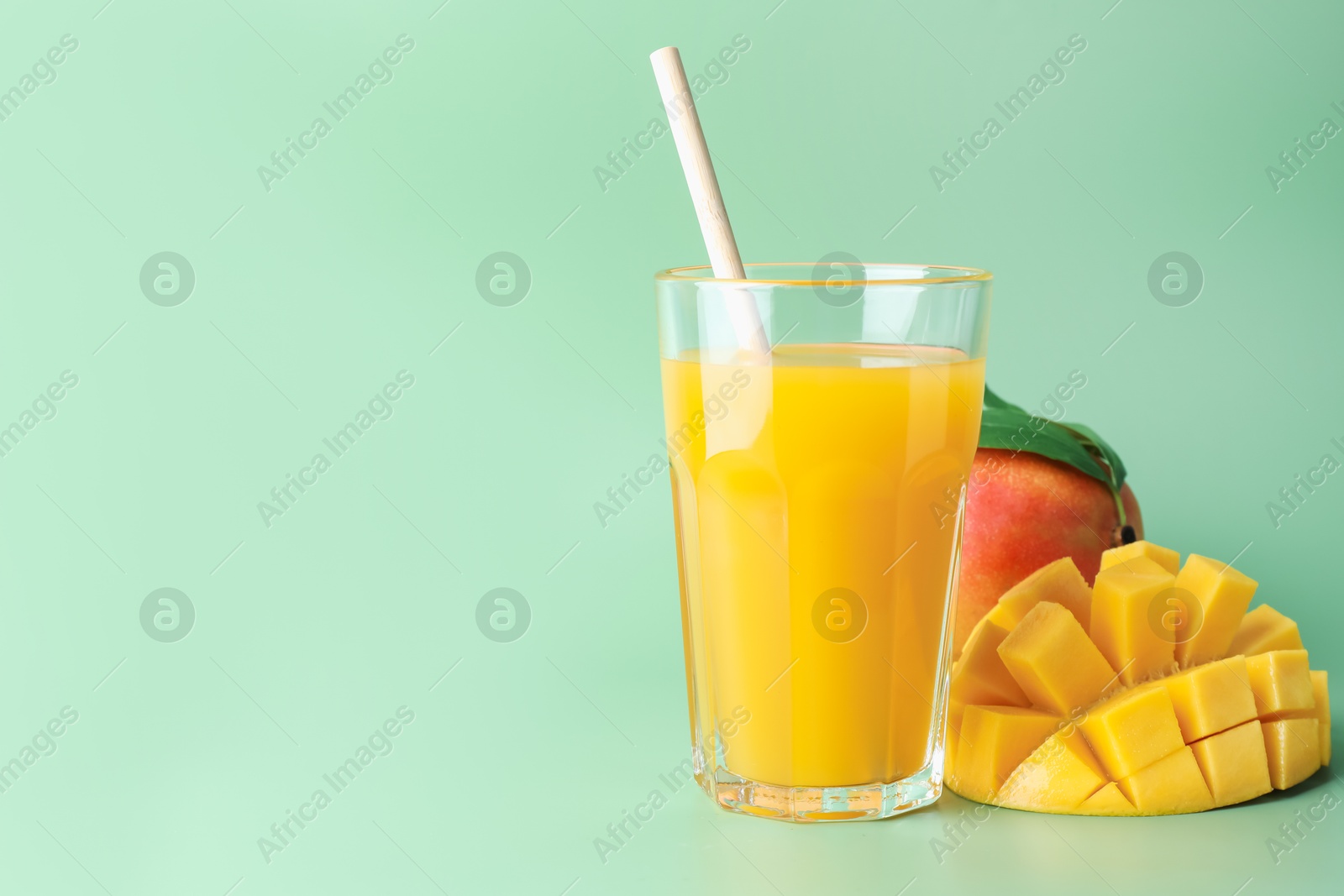 Tasty mango juice in glass and fresh fruits on green background, space for text Photo of Tasty mango juice in glass and fresh fruits on green background, space for text