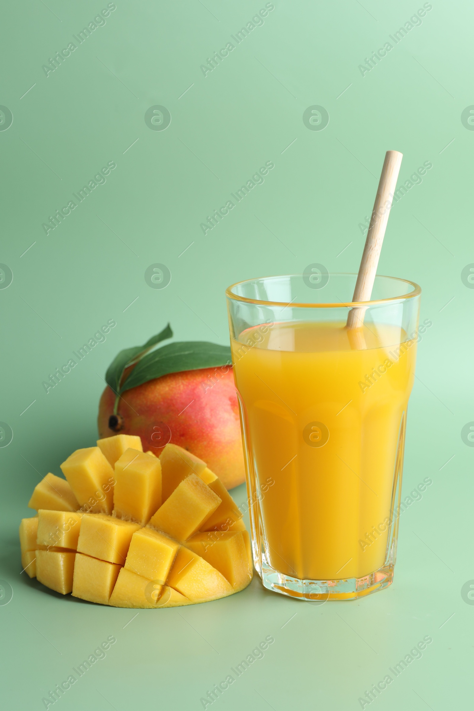 Tasty mango juice in glass and fresh fruits on green background Photo of Tasty mango juice in glass and fresh fruits on green background