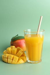 Photo of Tasty mango juice in glass and fresh fruits on green background