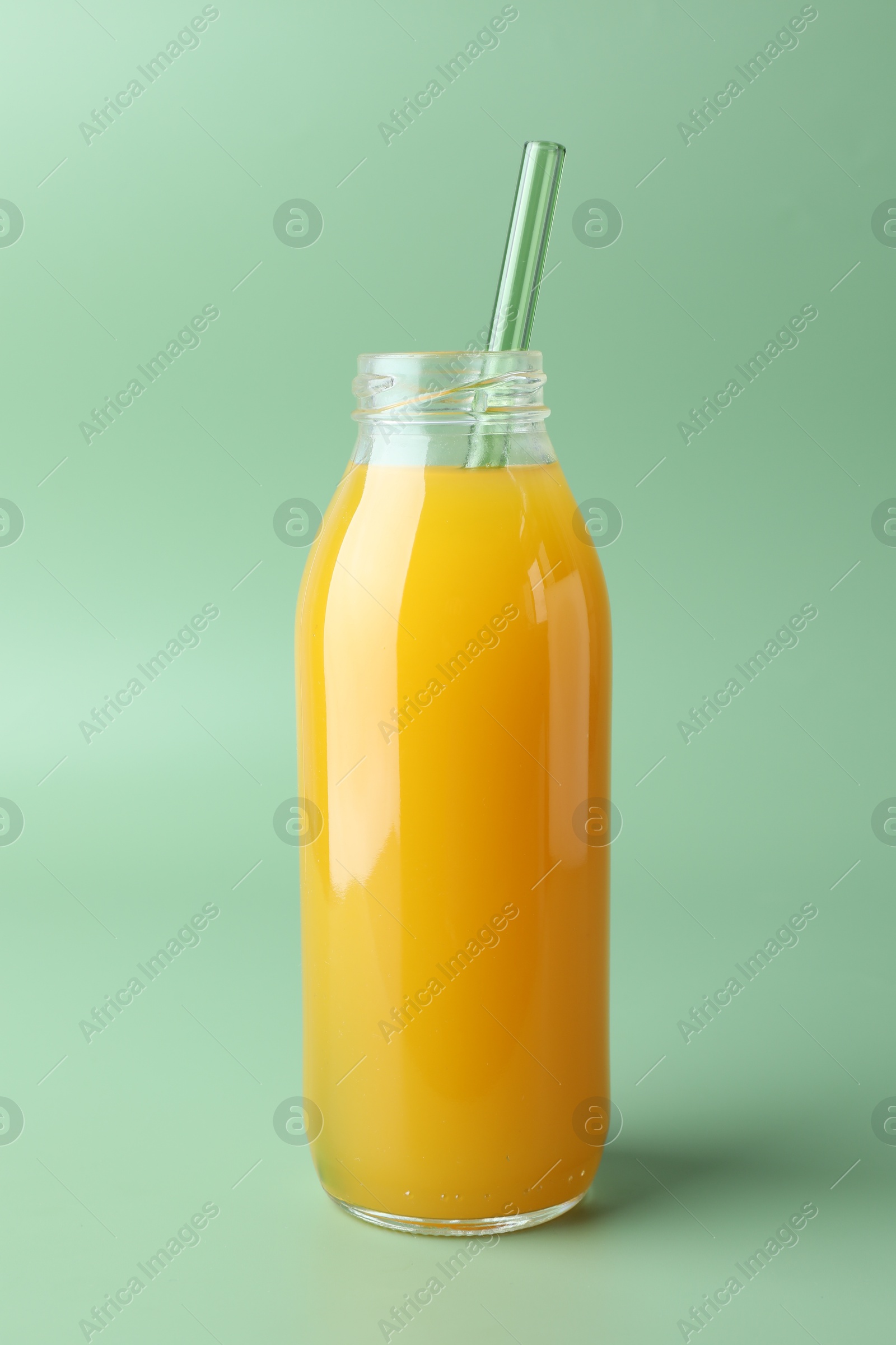 Tasty mango juice in glass bottle on green background Photo of Tasty mango juice in glass bottle on green background
