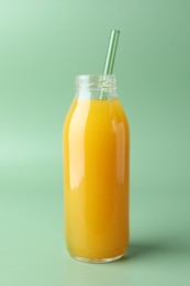 Photo of Tasty mango juice in glass bottle on green background