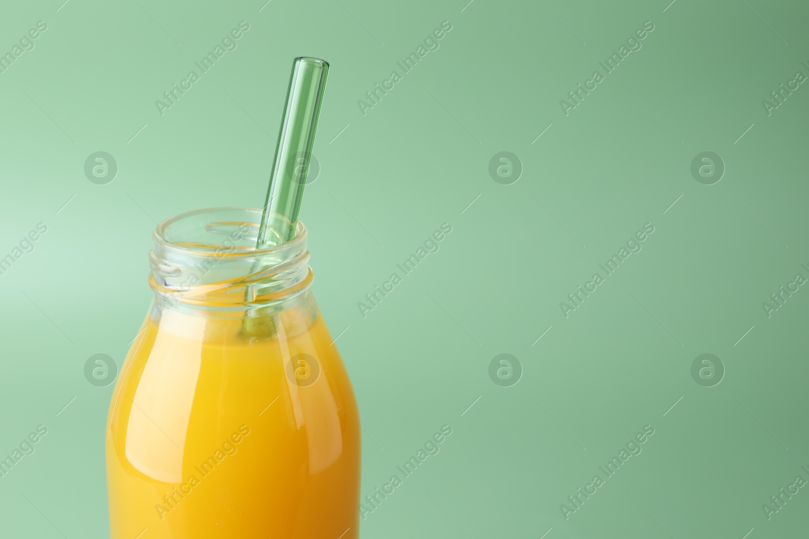 Tasty mango juice in glass bottle on green background, closeup. Space for text Photo of Tasty mango juice in glass bottle on green background, closeup. Space for text