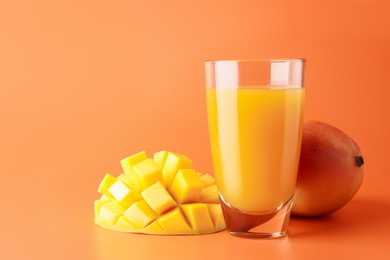 Photo of Tasty mango juice in glass and fresh fruits on orange background