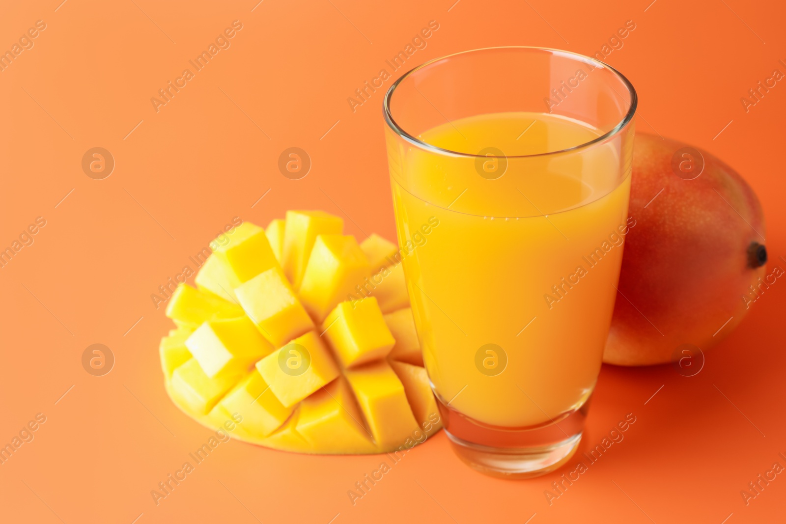 Tasty mango juice in glass and fresh fruits on orange background, closeup Photo of Tasty mango juice in glass and fresh fruits on orange background, closeup