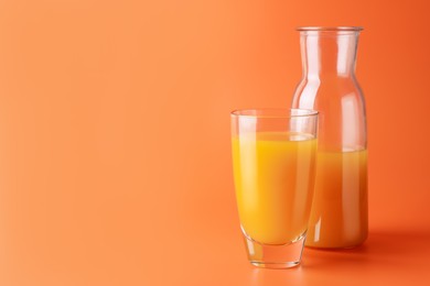 Photo of Tasty mango juice in glass and carafe on orange background, space for text