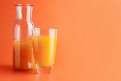 Photo of Tasty mango juice in glass and carafe on orange background, space for text