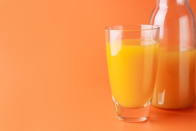 Photo of Tasty mango juice in glass and carafe on orange background, closeup. Space for text
