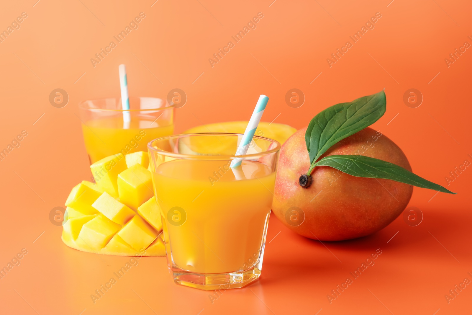 Tasty mango juice in glasses and fresh fruits on orange background Photo of Tasty mango juice in glasses and fresh fruits on orange background