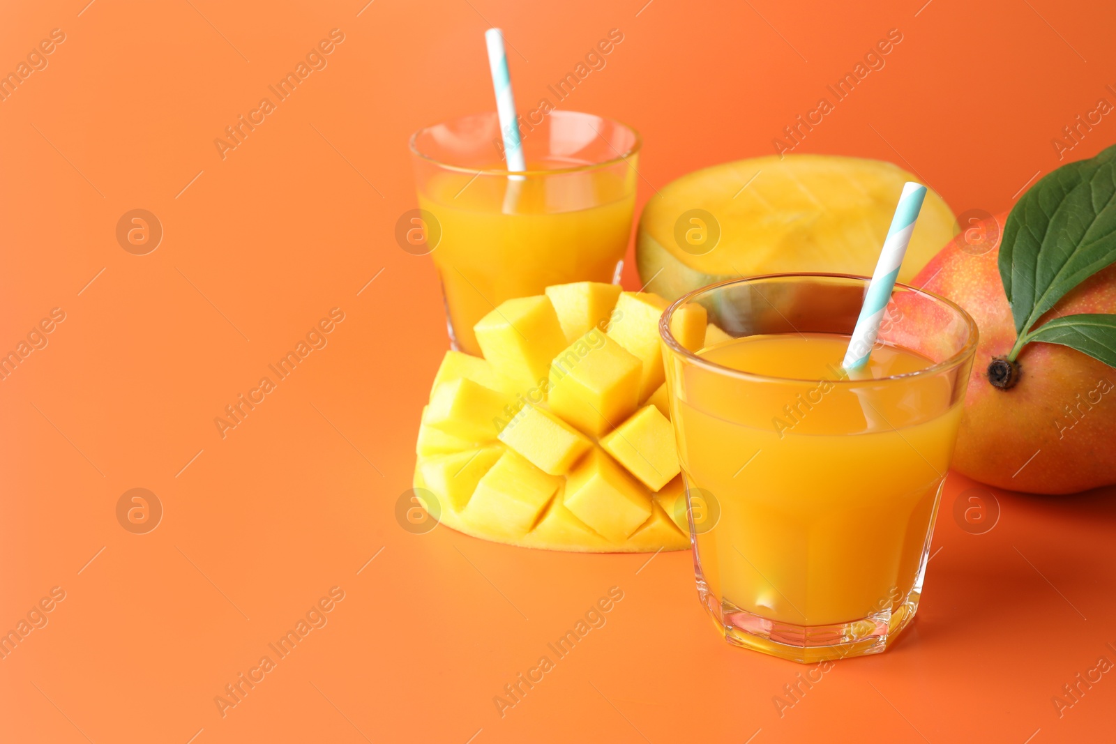 Tasty mango juice in glasses and fresh fruits on orange background, closeup. Space for text Photo of Tasty mango juice in glasses and fresh fruits on orange background, closeup. Space for text