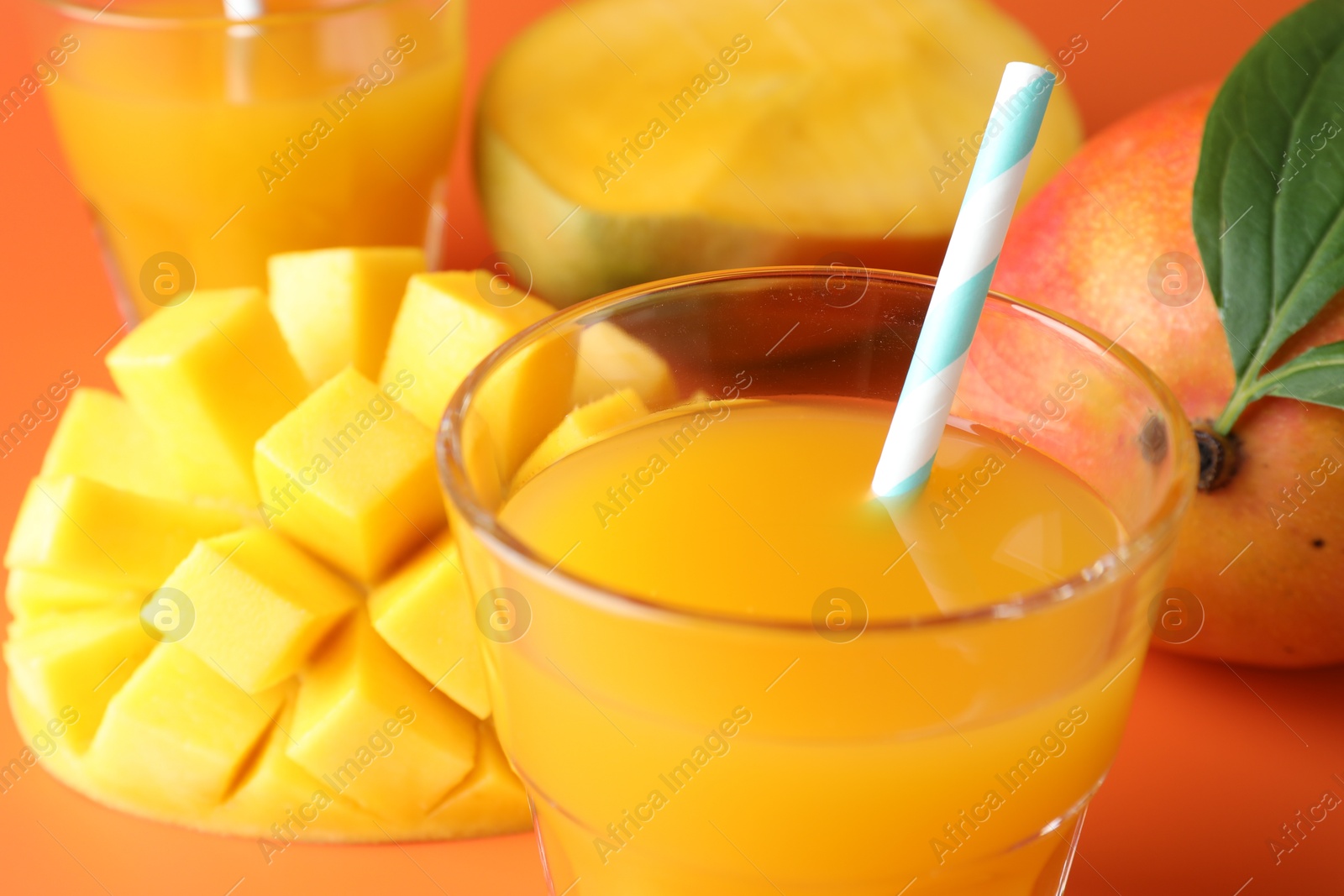 Tasty mango juice in glasses and fresh fruits on orange background, closeup Photo of Tasty mango juice in glasses and fresh fruits on orange background, closeup