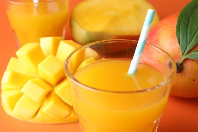 Photo of Tasty mango juice in glasses and fresh fruits on orange background, closeup