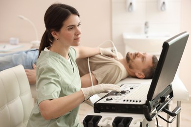 Photo of Sonographer conducting ultrasound examination of man's thyroid gland in clinic