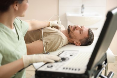Photo of Sonographer conducting ultrasound examination of man's thyroid gland in clinic, closeup
