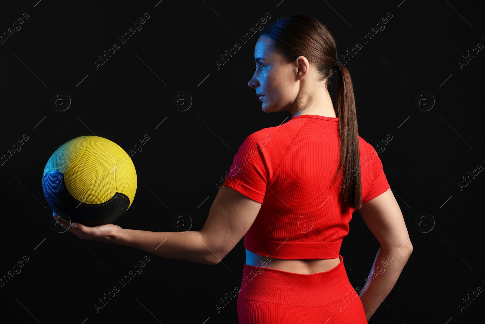 Woman with medicine ball on black background Photo of Woman with medicine ball on black background