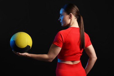 Photo of Woman with medicine ball on black background