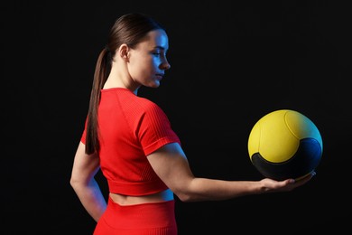 Photo of Woman with medicine ball on black background