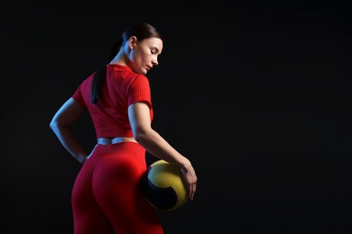 Photo of Woman with medicine ball on black background. Space for text