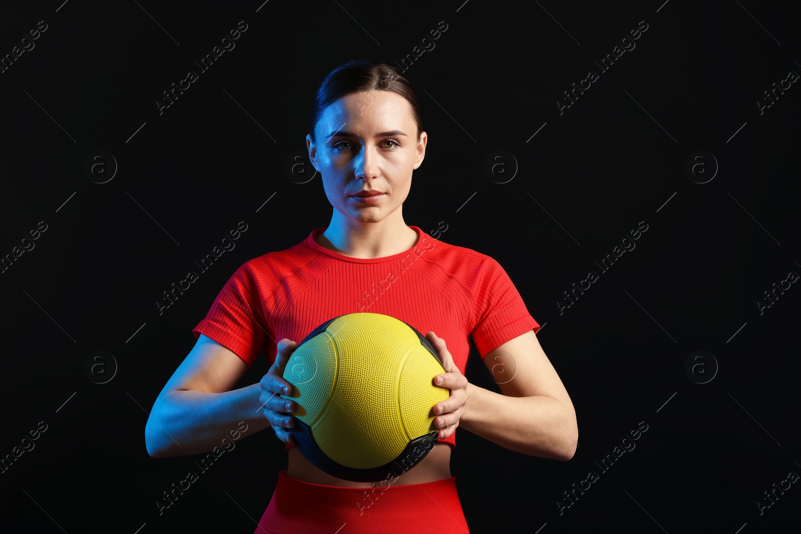 Woman with medicine ball on black background Photo of Woman with medicine ball on black background