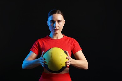 Photo of Woman with medicine ball on black background