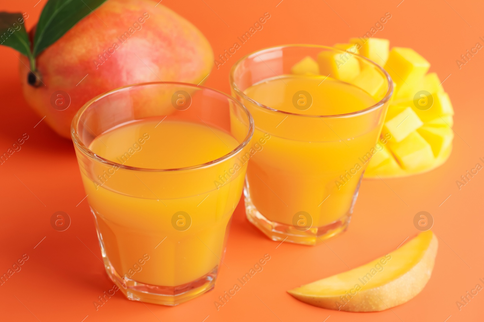 Tasty mango juice in glasses and fresh fruits on orange background, closeup Photo of Tasty mango juice in glasses and fresh fruits on orange background, closeup