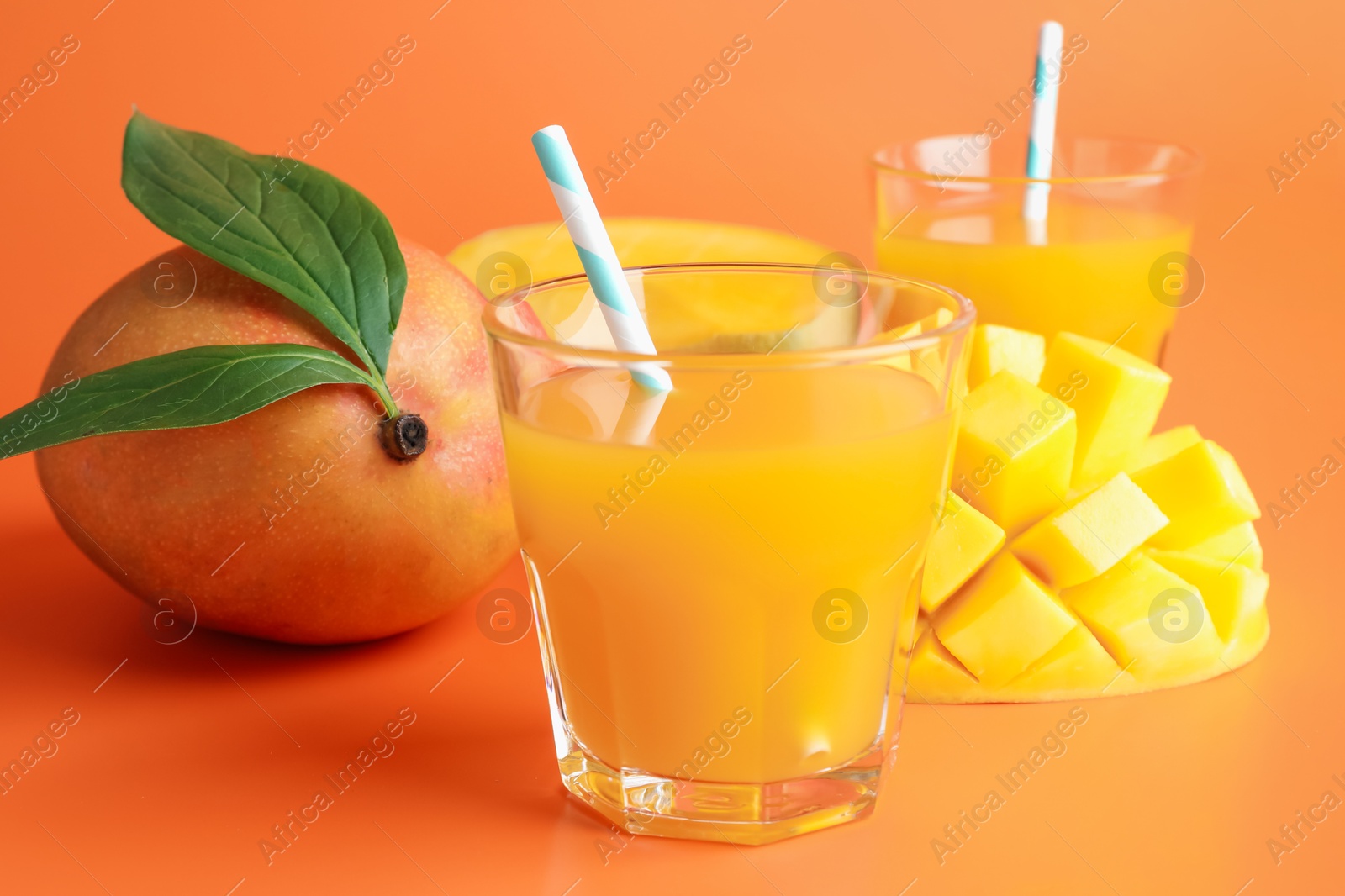 Tasty mango juice in glasses and fresh fruits on orange background, closeup Photo of Tasty mango juice in glasses and fresh fruits on orange background, closeup