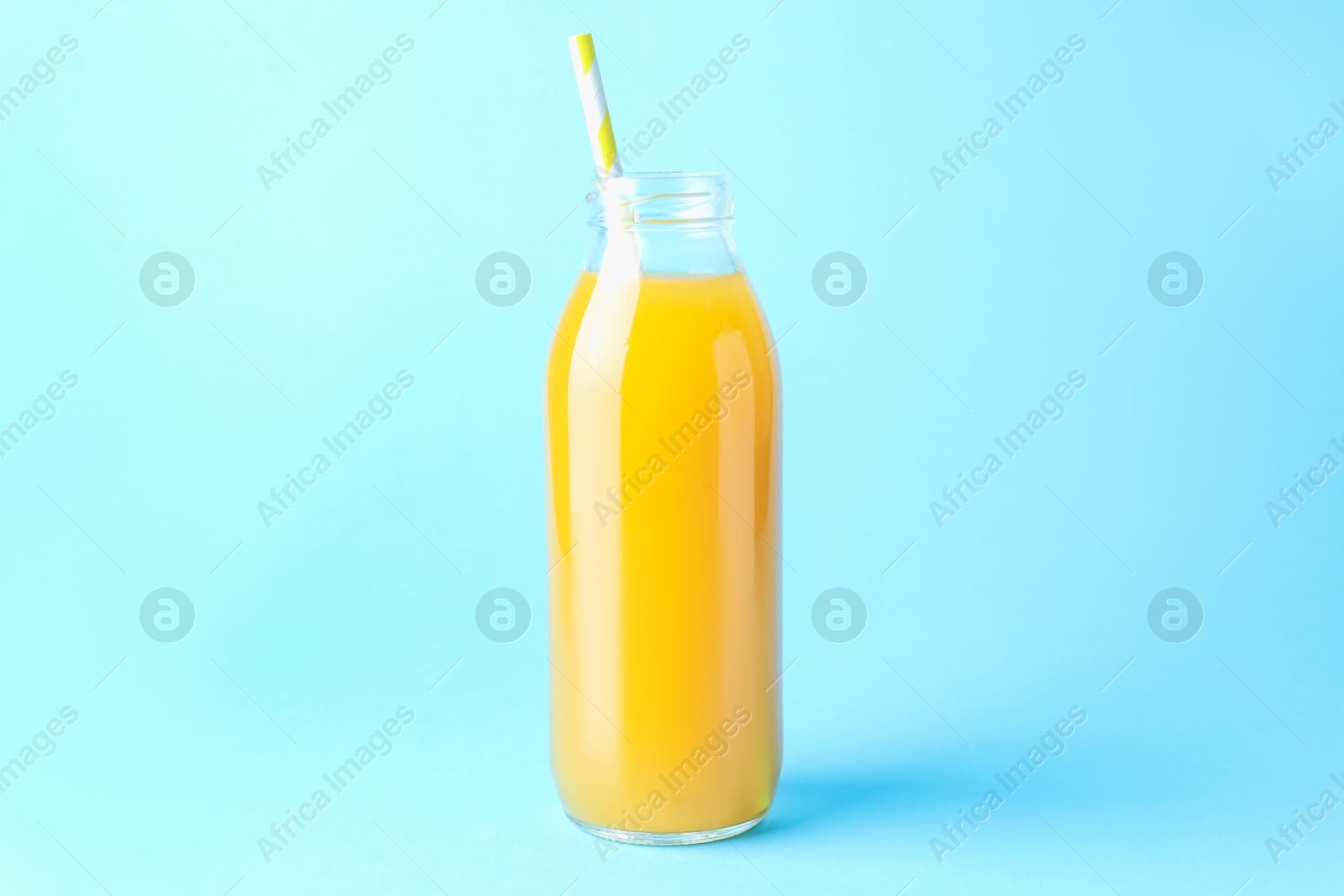 Tasty mango juice in glass bottle on light blue background Photo of Tasty mango juice in glass bottle on light blue background