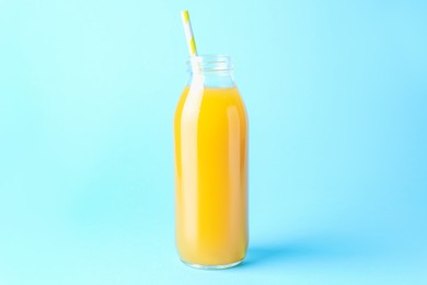 Photo of Tasty mango juice in glass bottle on light blue background