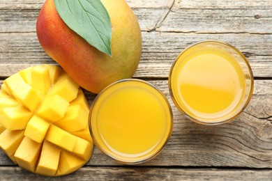 Photo of Tasty mango juice in glasses and fresh fruits on wooden table, flat lay