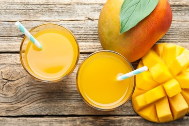 Photo of Tasty mango juice in glasses and fresh fruits on wooden table, flat lay